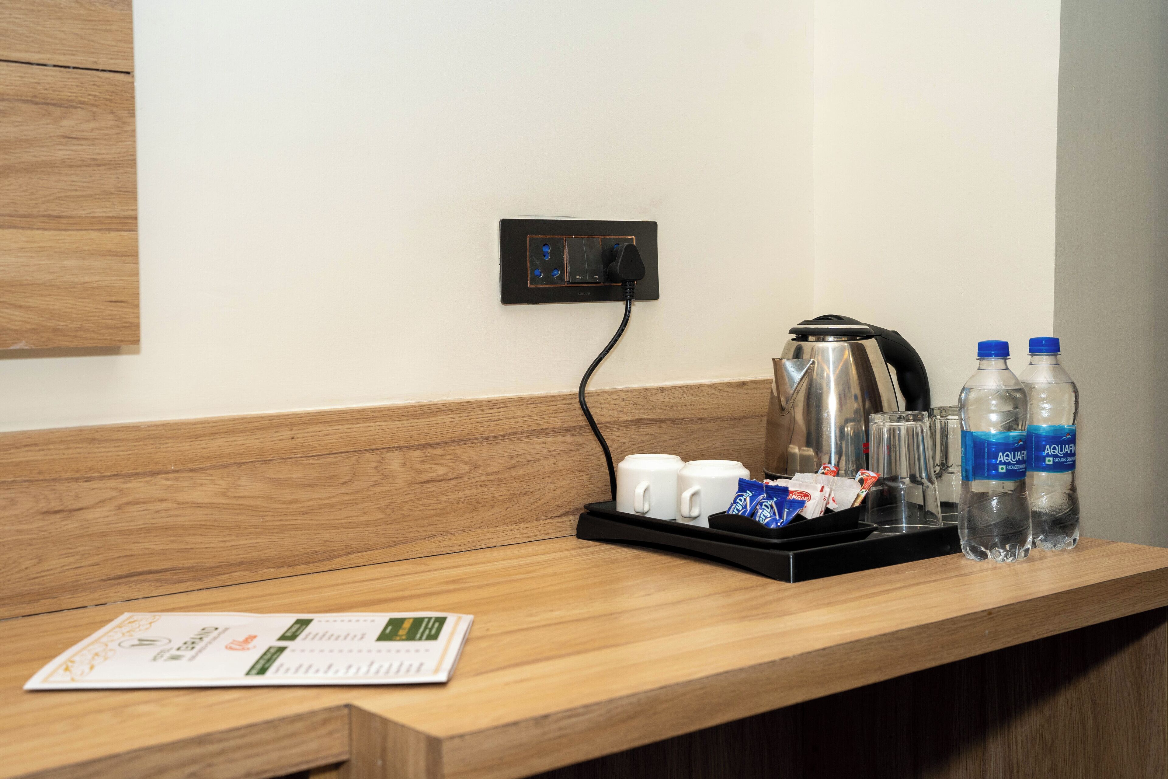 Un comptoir en bois avec une machine à café, deux bouteilles d’eau et un plateau contenant des tasses et des sachets.