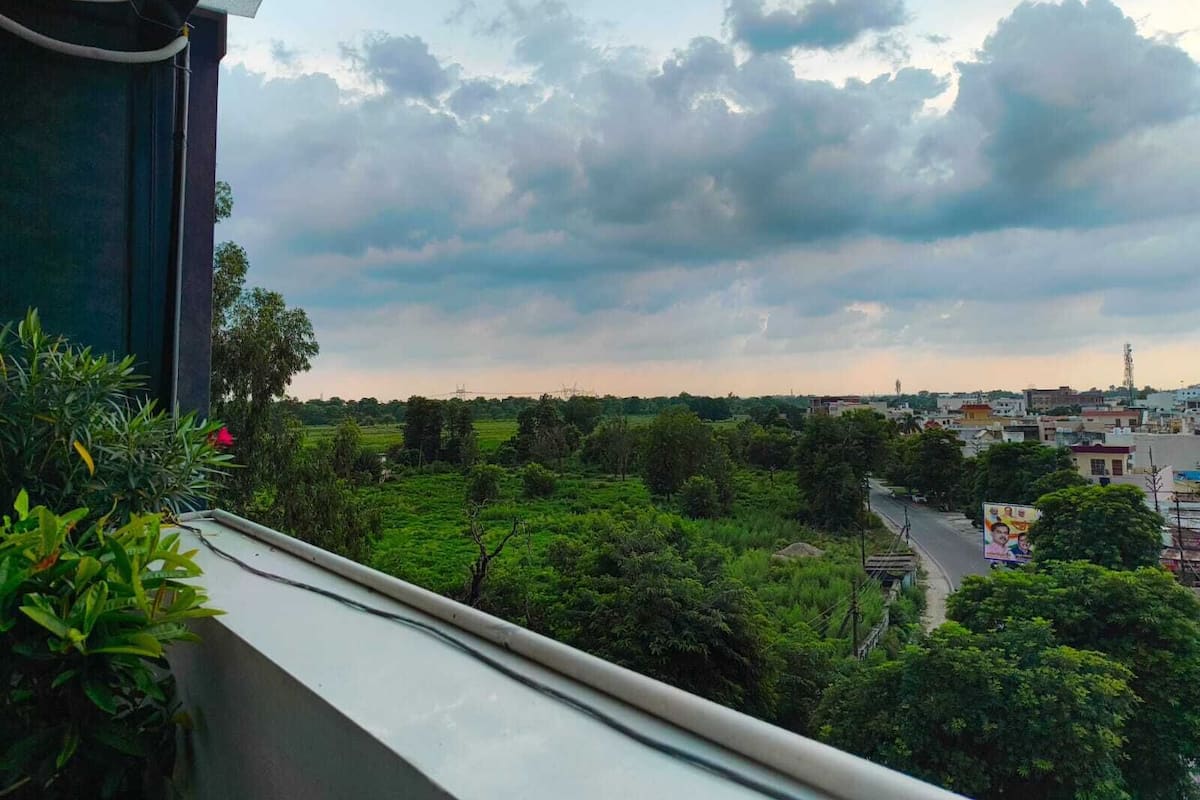 Ein Balkon mit Blick auf eine grüne Landschaft und eine Stadt in der Ferne.