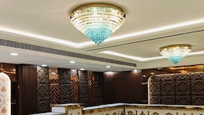 A lobby with a polished marble floor, ornate wall panels, and two chandeliers. - Hotel W Grand - A Boutique Hotel (Haridwar)