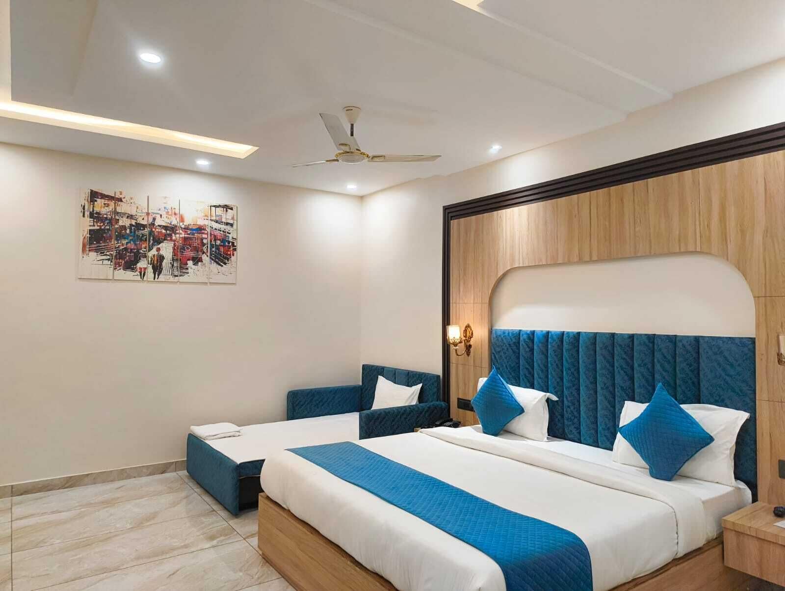 Una habitación de hotel moderna con una cama grande, dos mesitas de noche, un ventilador de techo y una obra de arte urbana en la pared.