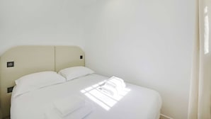 A clean, white hotel room with a bed, pillows, and neatly folded towels. - Modern apartment with terrace (Aubervilliers)