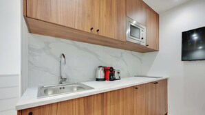 A modern kitchen with wooden cabinets, a stainless steel sink, a microwave, and a kettle on the countertop. - Modern apartment with terrace (Aubervilliers)