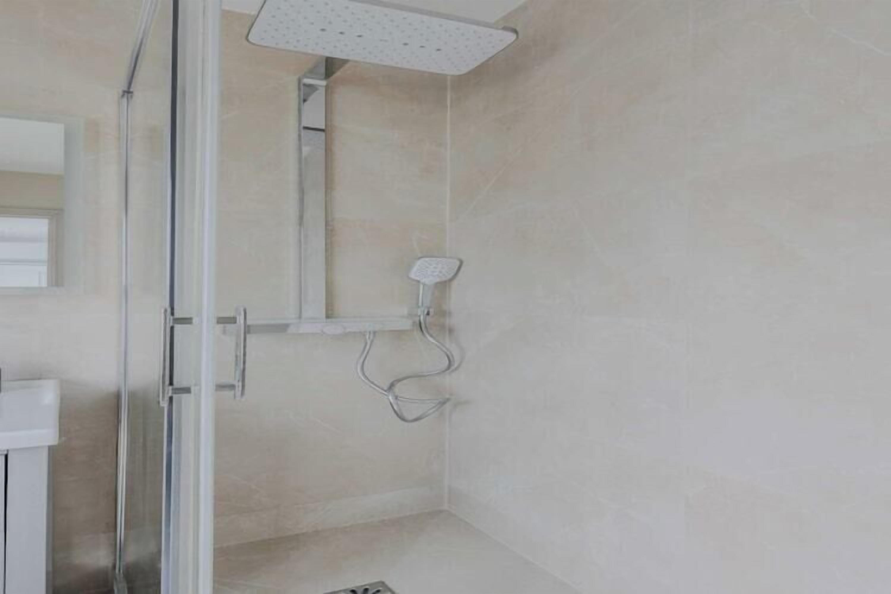 Ein modernes Badezimmer mit Duschkabine aus Glas, einem weißen Waschbecken und einem Spiegel.