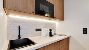Uma cozinha moderna com micro-ondas embutido, uma pia e uma cafeteira.