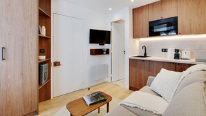 Uma sala de estar moderna com sofá, mesa de centro, televisão de tela plana, armários de madeira e eletrodomésticos embutidos.