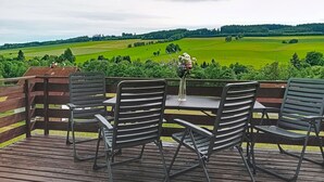 A wooden deck with metal chairs and a table, overlooking a green landscape with trees and fields. - Green Valley Park Stárkov 13 by Interhome (Stárkov)