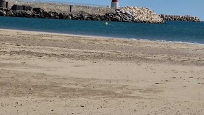 Ein Strand mit einem Leuchtturm auf einem Felsen.