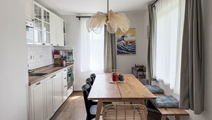 A modern kitchen with white cabinets, a wooden countertop, and a dining area with a wooden table and chairs.