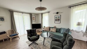 A modern living room with a sofa, two armchairs, a coffee table, and a TV.