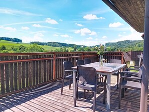 A wooden deck with a table and chairs, overlooking a green landscape with hills. - Green Valley Park Stárkov 7 by Interhome (Stárkov)