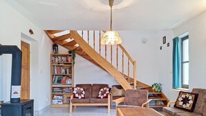En stue med en trætrappe, en reol, en sofa, et sofabord og en pejs.