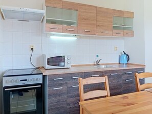 A compact kitchen with a stove, microwave, and sink.