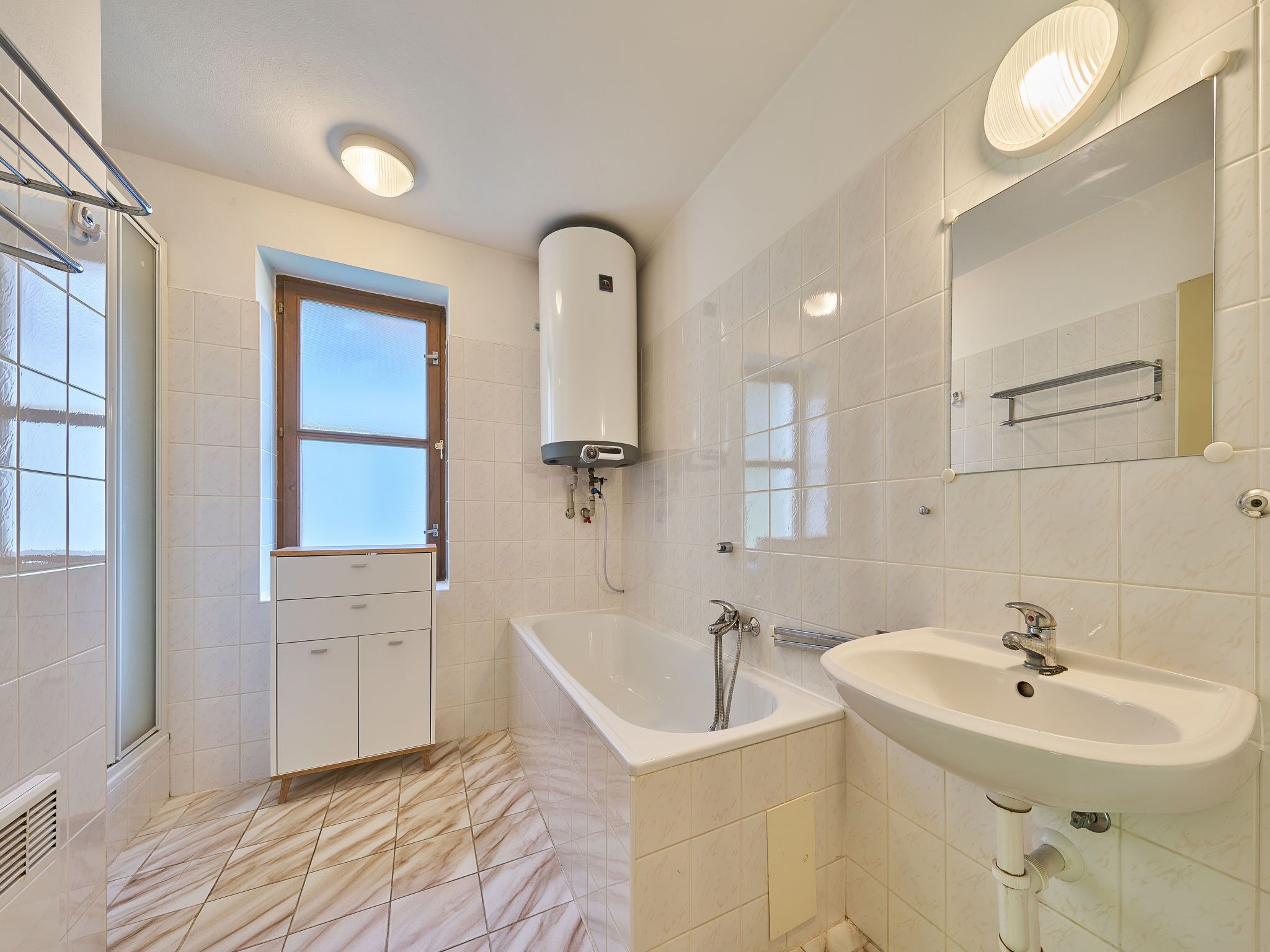 A modern bathroom with a bathtub, a sink, and a window.