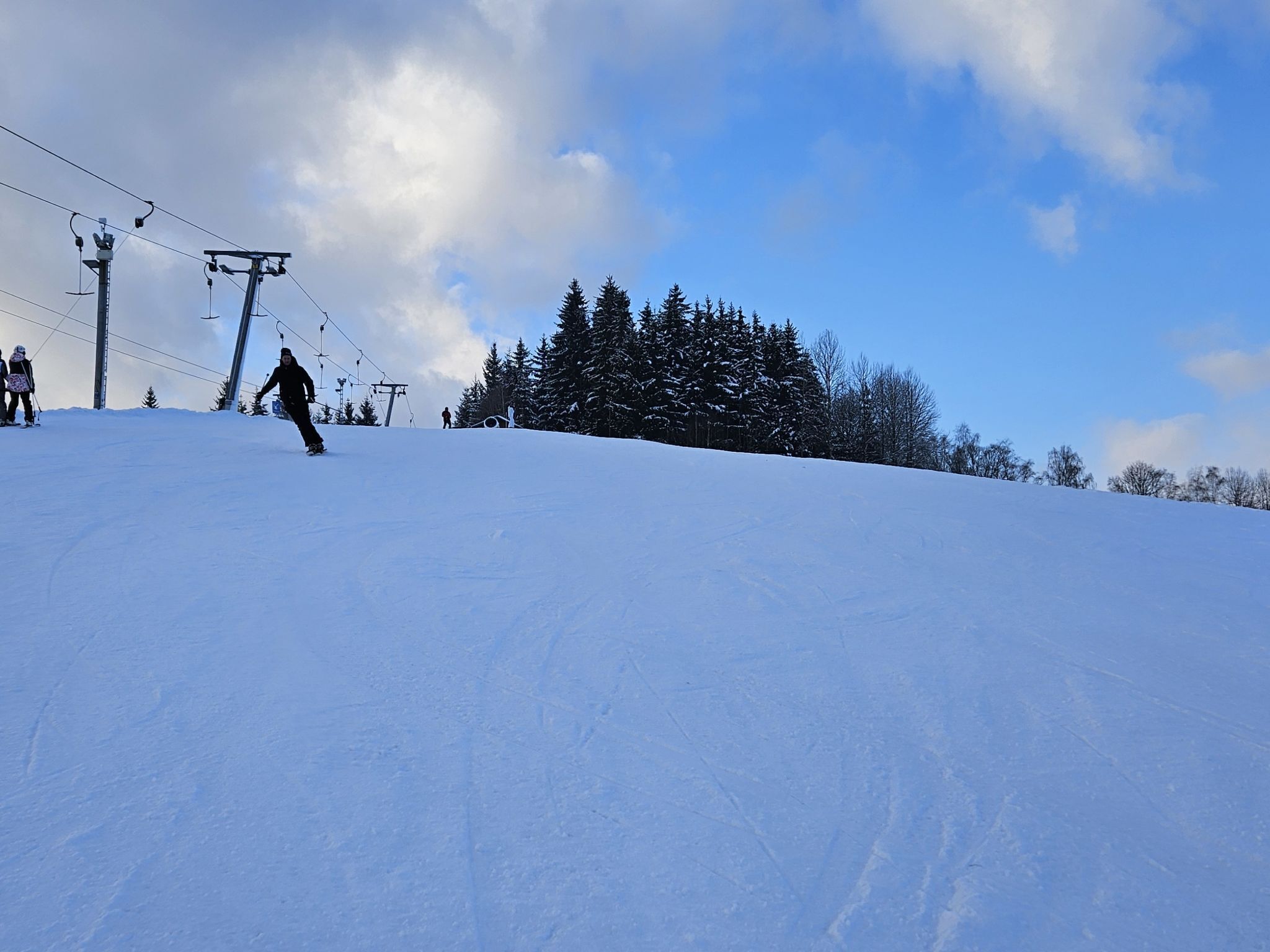 A snowy ski slope with a ski lift and trees in the background.