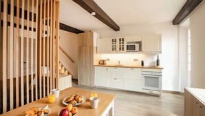 A modern kitchen with white cabinets, a wooden staircase, and breakfast items on the table. - Sublime flat sea view - Saint Tropez (Saint-Tropez)