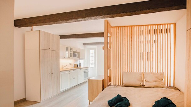 A bedroom with a bed, wooden slats, a wardrobe, and a kitchen in the background. - Sublime flat sea view - Saint Tropez (Saint-Tropez)