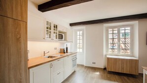 A kitchen with white cabinets, a wooden countertop, a microwave, and a window with a view of a tiled roof. - Sublime flat sea view - Saint Tropez (Saint-Tropez)