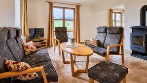 Un salón acogedor con un sofá, dos sillones, una mesita y una chimenea.