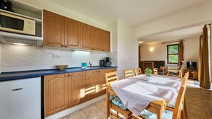 Una cocina moderna con armarios de madera, microondas integrado y una zona de comedor con mesa y sillas.