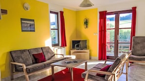 A living room with a sofa, chairs, a TV, and a red rug. - Green Valley Park Stárkov 17 by Interhome (Stárkov)