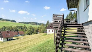 A residential area with a wooden staircase leading to a white building, surrounded by green fields and houses with red roofs. - Green Valley Park Stárkov 17 by Interhome (Stárkov)