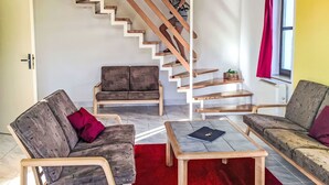 A modern living room with a wooden staircase, two sofas, a coffee table, and a red rug. - Green Valley Park Stárkov 17 by Interhome (Stárkov)
