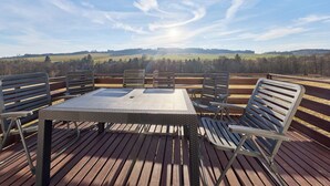 A wooden deck with a table and chairs, overlooking a scenic landscape. - Green Valley Park Stárkov 20 by Interhome (Stárkov)