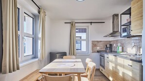 A compact kitchen with a dining area, a built-in oven, and a window with curtains. - Green Valley Park Stárkov 20 by Interhome (Stárkov)