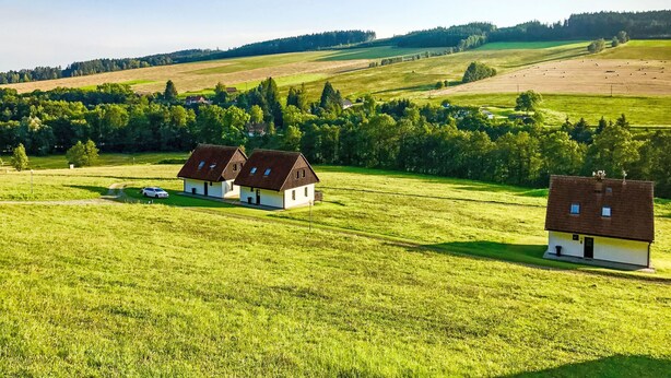 A rural landscape with two white houses with brown roofs, surrounded by green fields and trees. - Green Valley Park Stárkov 20 by Interhome (Stárkov)