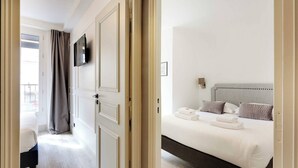 Une chambre d’hôtel avec un lit, un téléviseur fixé au mur et une vue sur le balcon extérieur.