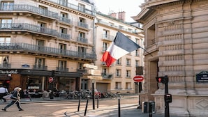 A street scene with a building featuring ornate balconies and a flag.