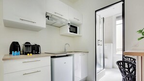 A compact kitchen with a microwave, coffee maker, and a small refrigerator.