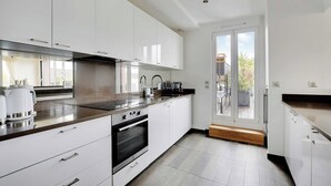 A modern kitchen with white cabinets, stainless steel appliances, and a large window. - Stunning apartment - 3BR/6P - La DÃ©fense (Courbevoie)