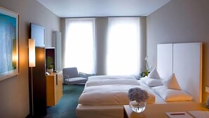 A hotel room with a bed, a desk, a chair, a TV, and a large window.
