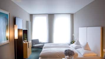 A hotel room with a bed, bedside table, lamp, chair, TV, and a large window.