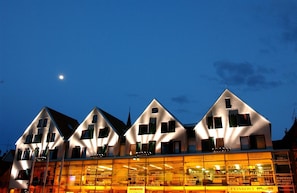 Una hilera de edificios modernos con techos triangulares y grandes ventanales, probablemente un hotel o un complejo comercial.