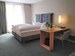A hotel room with a bed, bedside table, lamp, and a chair.