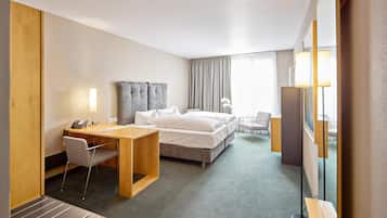 A hotel room with a bed, desk, chair, and a large mirror.