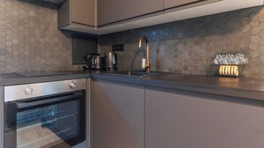 Uma cozinha moderna com forno Bosch, cafeteira e chaleira no balcão.