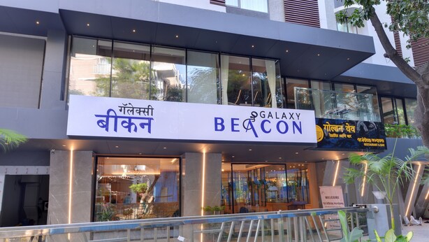 A modern building with a sign for 'Galaxy Beach' and 'Gallekshi Beach'. - Galaxy Beacon Hotel (Mumbai)