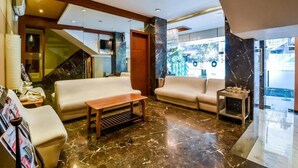 A modern lobby with a marble floor, leather sofas, a wooden coffee table, and a staircase leading to another level. - Galaxy Beacon Hotel (Mumbai)