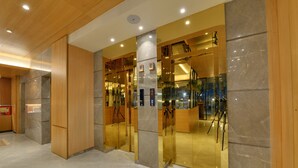 A modern hotel lobby with a marble floor, wooden paneling, and glass doors leading to the reception area. - Galaxy Beacon Hotel (Mumbai)