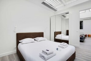 Une chambre d’hôtel moderne avec un grand lit, un miroir et un dressing.