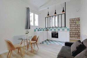 A modern kitchen with a checkered floor, a dining area with two chairs, a sofa, and a bookshelf. - Intimate apartment - 1BR/4P - Saint-Lambert (Paris)