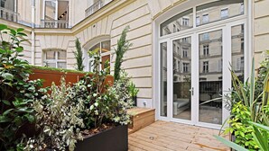 A wooden deck with planters and a glass door leading to a balcony.