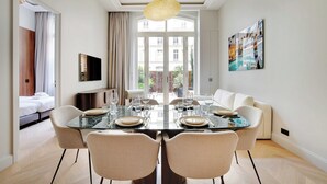 A modern dining area with a glass table, four chairs, and a chandelier.