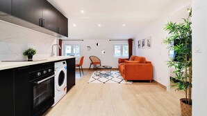 A compact living space with a kitchen area, a sofa, and a dining table. - Welcoming apartment -1BD/4P - 18th arrd (Paris)