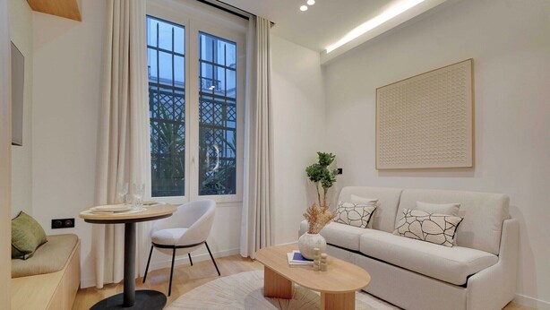 A modern living room with a sofa, a round coffee table, a dining table with chairs, and a large window with curtains. - Modern studio - 2P - Clignancourt (Paris)