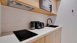 A modern kitchen with a built-in induction cooktop, a coffee maker, a toaster, and a microwave. - Modern studio - 2P - Clignancourt (Paris)
