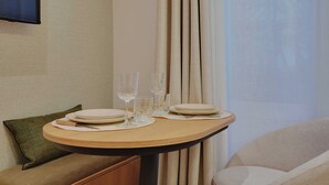 A dining table set with plates and glasses, a green pillow, and a wooden bench. - Modern studio - 2P - Clignancourt (Paris)